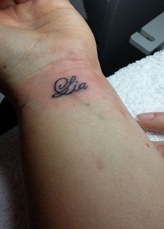 Tattoo am linken Handgelenk den Namen Lia in der Farbe schwarz tätowiert