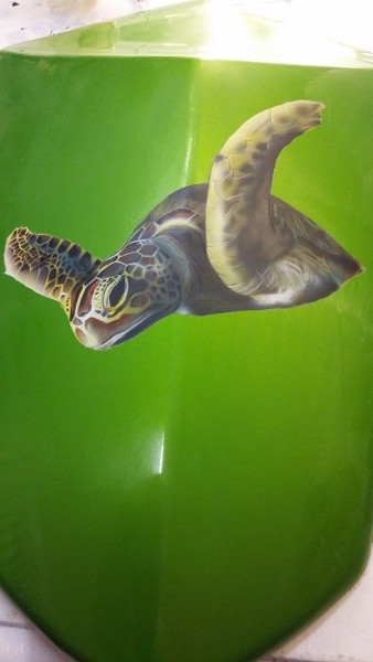grünes Motorradteil als Untergrund- darauf ist eine Wasserschildkröte geairbrusht in einem braunton