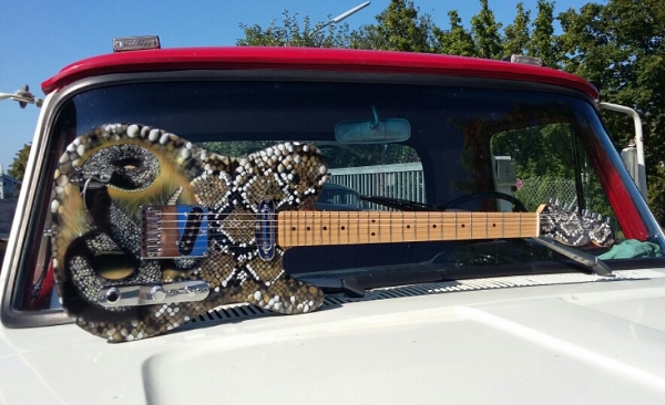Gitarre in braun und schwarztönen wurde ein Schlangenmuster auf eine E-Gitarre geairbrusht. Auf dem Schlangenmuster wurde eine Schlange geairbrusht.