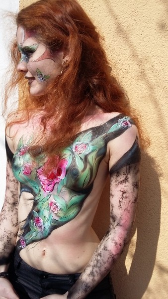 Bodypainting- es wird der Oberkörper mit bunten Blumen bemalt. in rot und lilatönen die Blätter sind grün