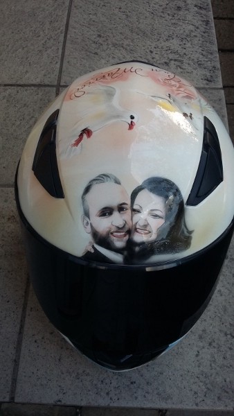 auf einem weißen Helm wurde das Hochzeitspaar porträtiert umramt mit weißen Tauben