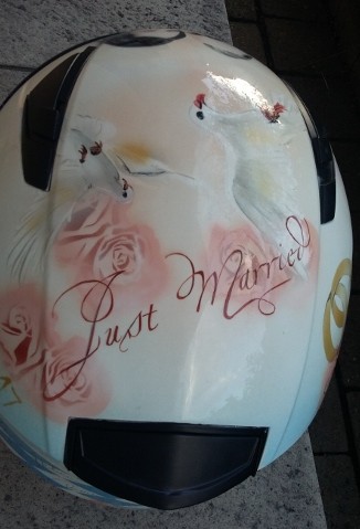 auf einem weißen Helm wurde das Hochzeitspaar porträtiert umramt mit weißen Tauben