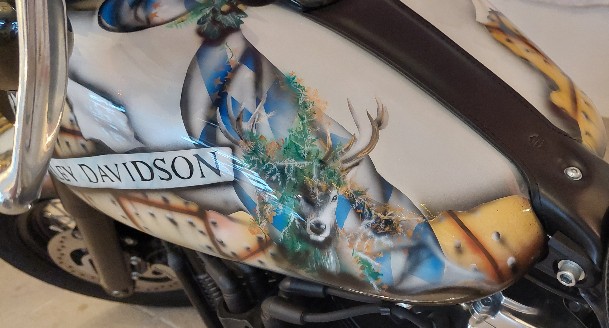 die schwarze Harley wurde in einem Braunton geairbrusht in Form eines aufgerissenem Blech mit vielen schwarzen Nieten. ein in braungehatenen Hirsch wurde auf der linken Seite geairbrusht hinten ein fuchs in lachsrot geairbrusht