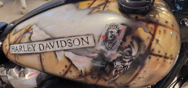 die schwarze Harley wurde in einem Braunton geairbrusht in Form eines aufgerissenem Blech mit vielen schwarzen Nieten. ein in braungehatenen Hirsch wurde auf der linken Seite geairbrusht hinten ein fuchs in lachsrot geairbrusht