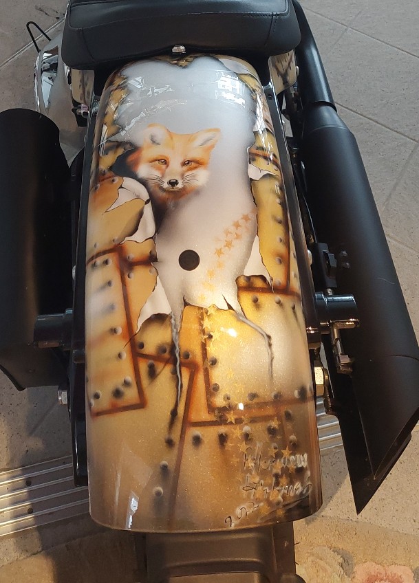 die schwarze Harley wurde in einem Braunton geairbrusht in Form eines aufgerissenem Blech mit vielen schwarzen Nieten. ein in braungehatenen Hirsch wurde auf der linken Seite geairbrusht hinten ein fuchs in lachsrot geairbrusht