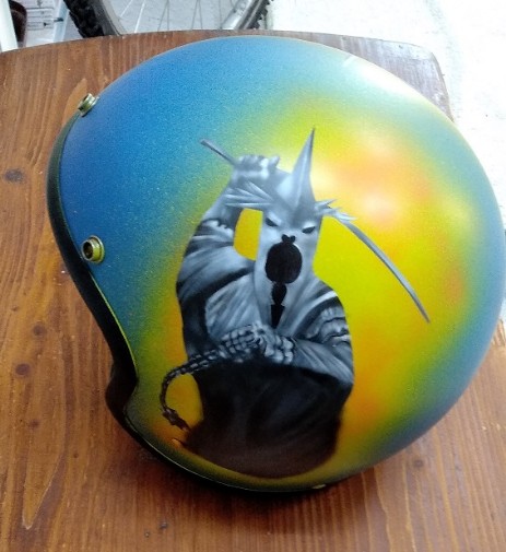 blauer Airbrush-Helm mit einem Ungeheuer in schwarz mit einem orang-gelb en Hintergrund
