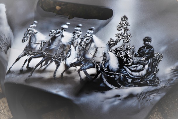 auf einem schwarzen Mototrradteil ist in weiß und grau der König Ludwig in seinem Schlitten und 4 Pferden geairbrusht und gemalt