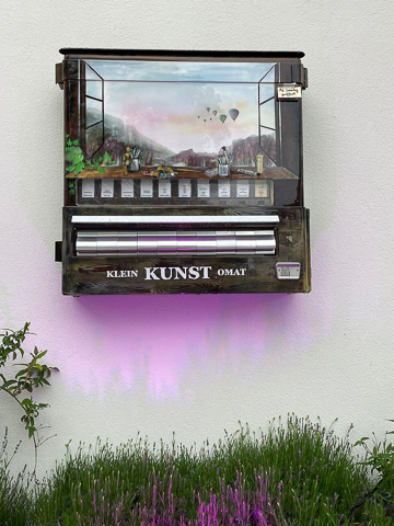 es wurde ein Zigarrettenautomat umfunktioniert in ein Automat von dem man selbstgemachte Geschenkartikel ziehen oder kauten kann. Er wurde in einem braunton geairbrusht und gemalt. im Himmel befinden sich Ballone