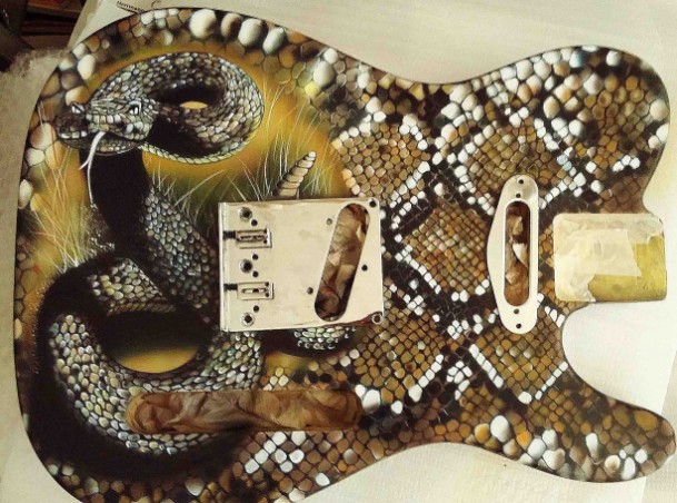 E-Gitarre mit Schlangenmotivhintergrund, auf dem Schlangenhintergrund ist eine Schlange draufgesetzt. Die Farben sind weiß,schwarz,brauntöne und gelb. Hinterder Schlange sind Grashalme in weiß und naturfarben