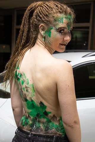 ein Event in einem Autohaus unter vielen neuen Autos. Bodypainting in grün für die Natur