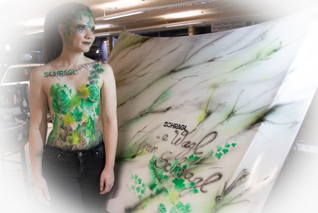 ein Event in einem Autohaus unter vielen neuen Autos. Bodypainting in grün für die Natur