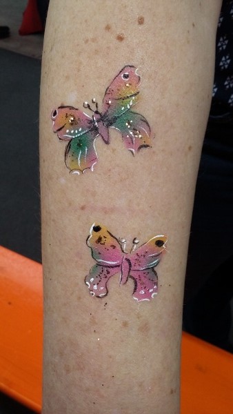 Bodypainting Schmetterlinge am Unterarm. Die Schmetterlinge sind in mehrere Farben angebracht und mit Muster verziehrt.