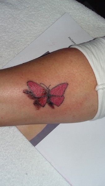 auf dem rechten Unterarm wurde in rot ein Schmetterling tätowiert mit Schatten in dunkelgrau